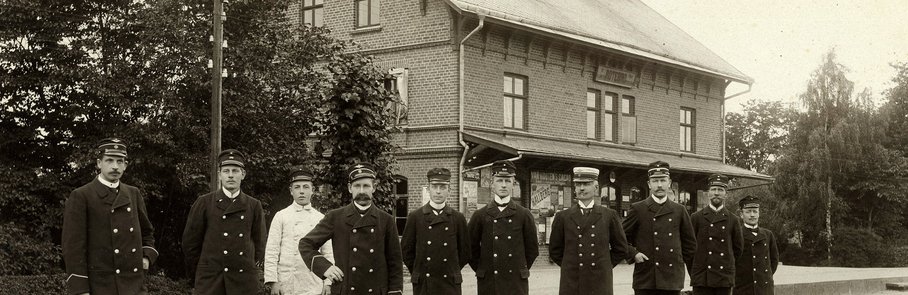 En grupp män som står framför en tågstation.