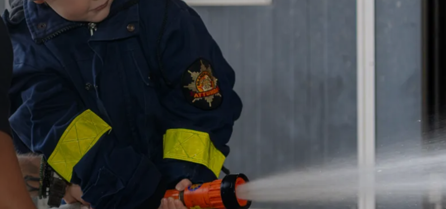 Barn sprutar vatten med brandslang