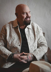 Anders Bagge sitter i en stol med knäppta händer och tittar åt sidan. Framför honom ligger en hatt.