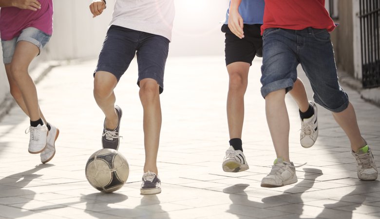 Children playing with soccer ball in alley