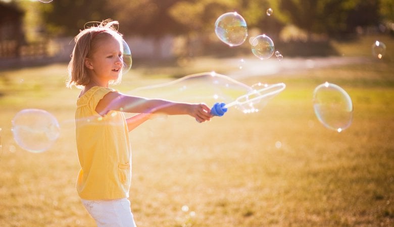 Young girl making large bubble in park