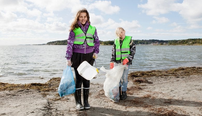 Flickor som plockar skräp på en strand.
