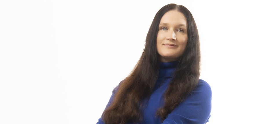 Kvinna med mörkt hår som sitter i en stol med benen i kors