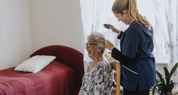 Hemtjänstpersonal hjälper äldre kvinna i hemmet