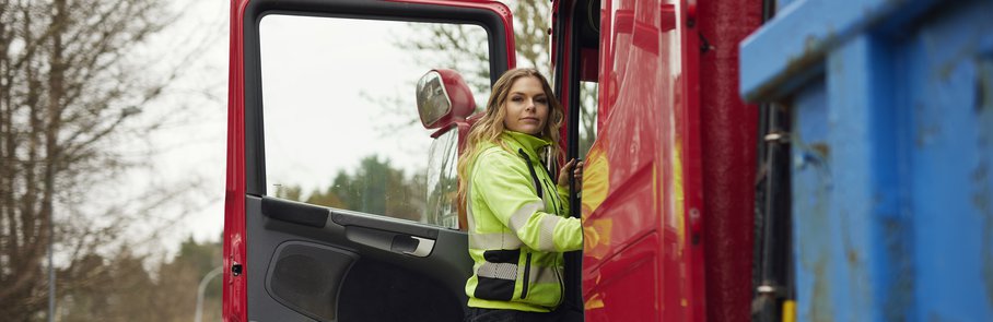 Kvinna i varselkläder vid lastbil