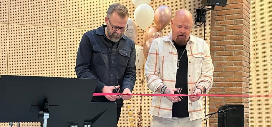 Två män på en scen som klipper ett invigningsband