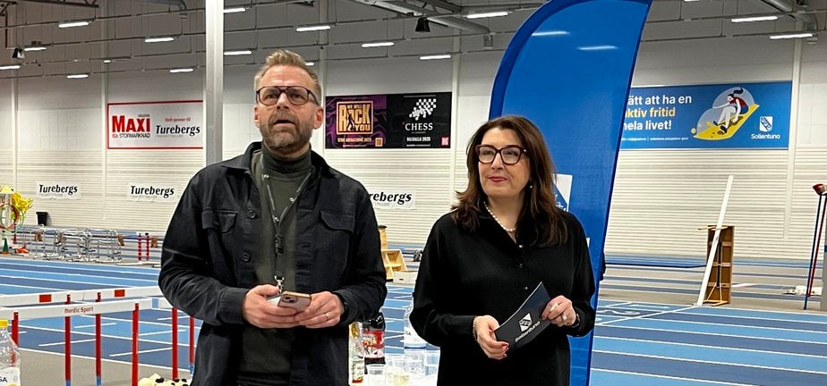 Två personer som står och talar i bredvid ett bord en idrottshall