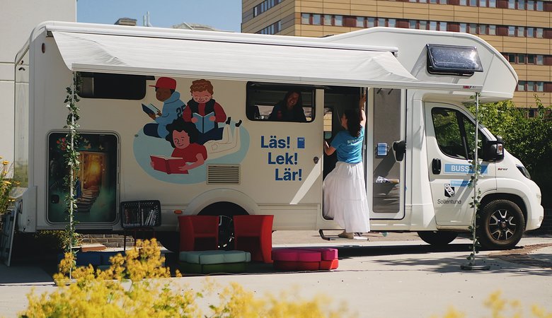 En husbil som står parkerad framför en hög byggnad.