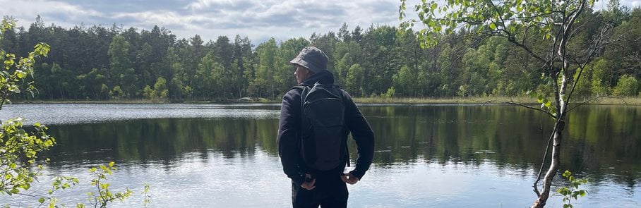 En man som står bredvid en hund nära en sjö i södra Törnskogens naturreservat.