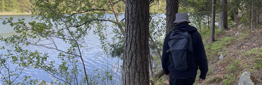 En man med ryggsäck går längs en stig vid Rösjön.