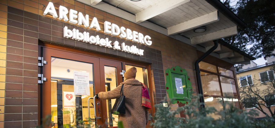 En kvinna går in i en byggnad med en röd dörr.