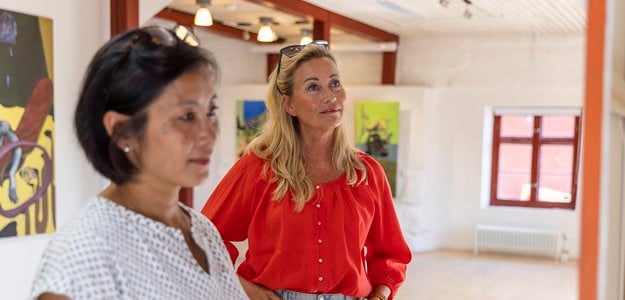 Två kvinnor tittar på konst i konsthallen på Stallbacken kultur.