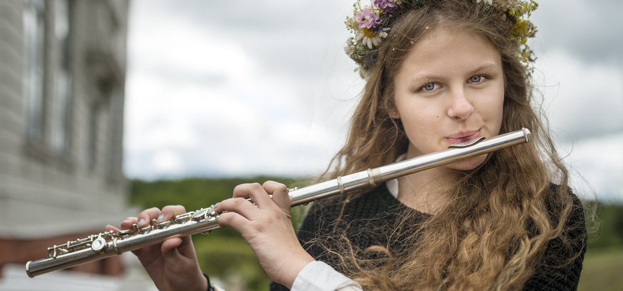 Ung kvinna med tvärflöjt och blommor i hår