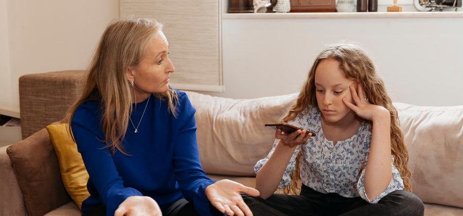 Mamma och tonårsdotter har en diskussion om mobiltelefonen.