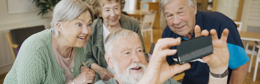 Disabled senior man taking selfie with friends at retirement home