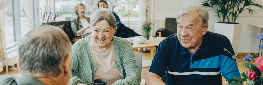 Elderly senior friends talking while sitting at dining table in nursing home