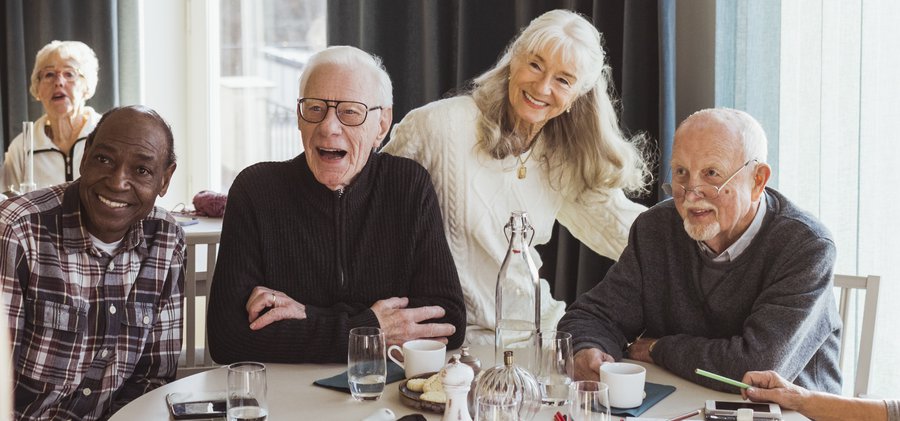 Male nurse photographing senior men and women at retirement home
