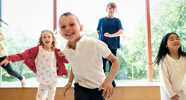 Cheerful children running while playing at elementary school