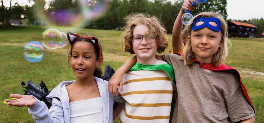 Portrait of boy wearing superhero custome while standing with friend in summer camp