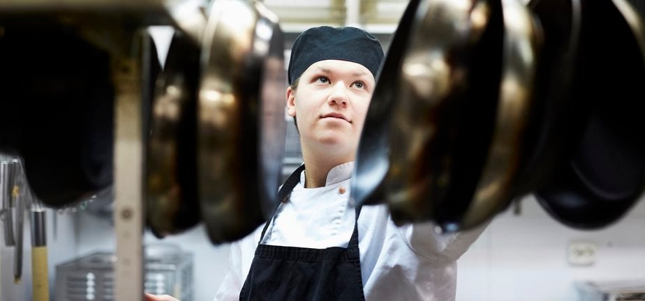 Male chef arranging frying pan in commercial kitchen