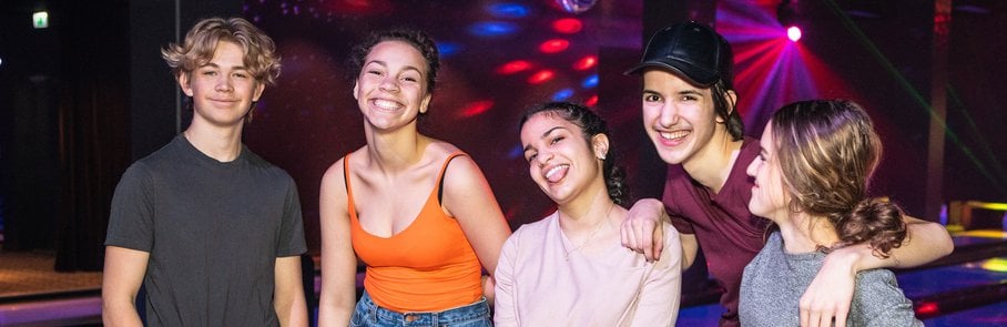 Portrait of smiling multi-ethnic teenagers standing on parquet floor at bowling alley