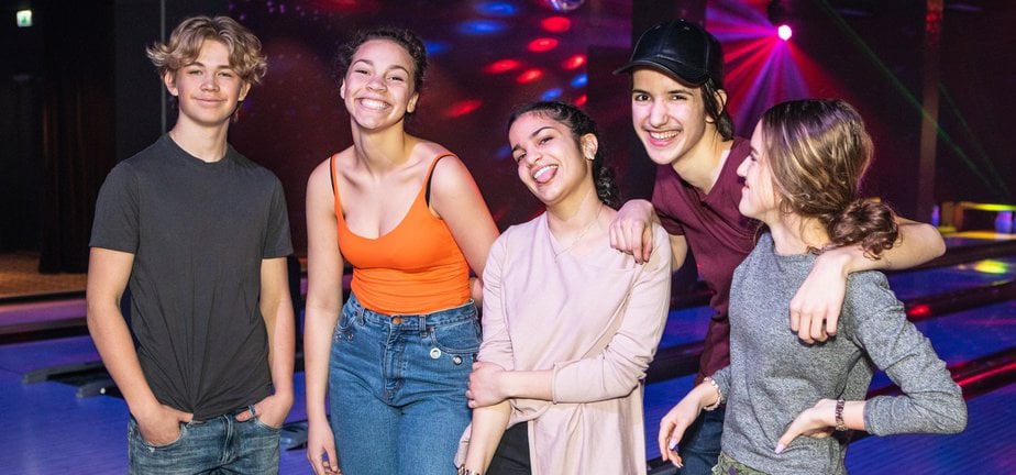 Portrait of smiling multi-ethnic teenagers standing on parquet floor at bowling alley