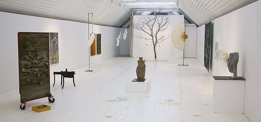 Ett rum fyllt med skulpturer och ett träd.