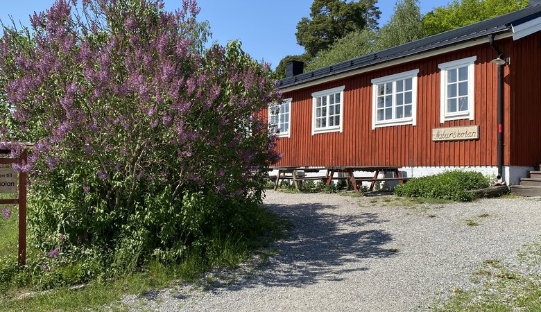 Ett rött hus som ligger på ett grönskande fält.