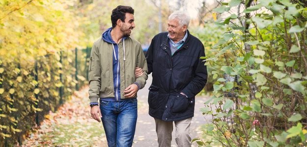 Happy senior man with caretaker walking in park