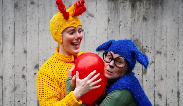 Två utklädda personer som håller i en röd ballong.