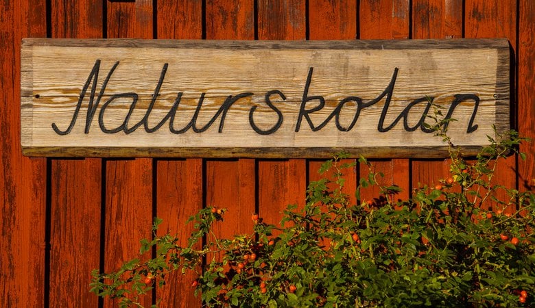 En träskylt på en röd träbyggnad.