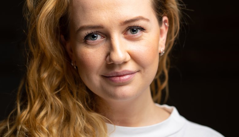 Porträttbild av Norea Samuelsson som tittar in i kameran och ler med stängd mun.