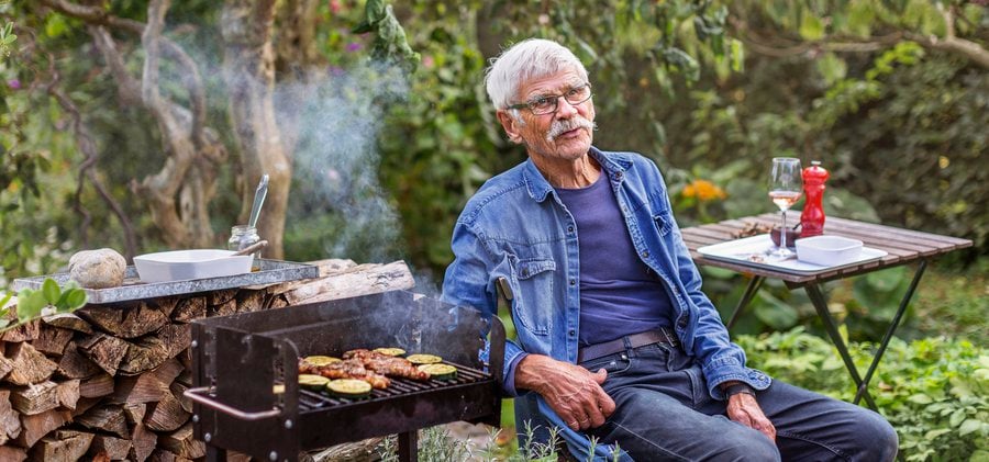 äldre man grillar i sin trädgård