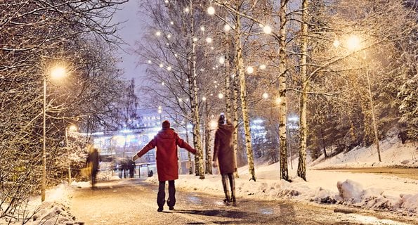 Två personer går längs en snöig stig och håller varandra i handen.